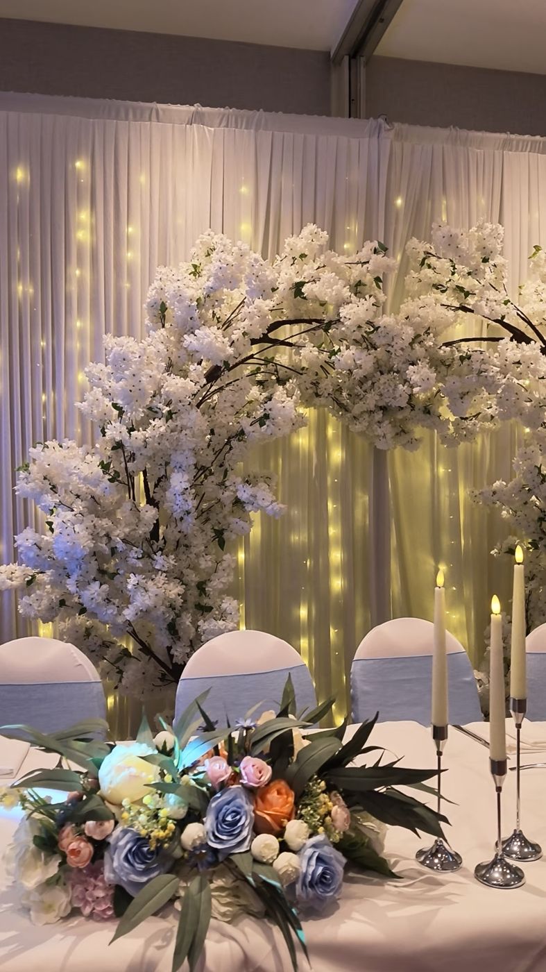 White blossom arch with fairy lights behind a top table
