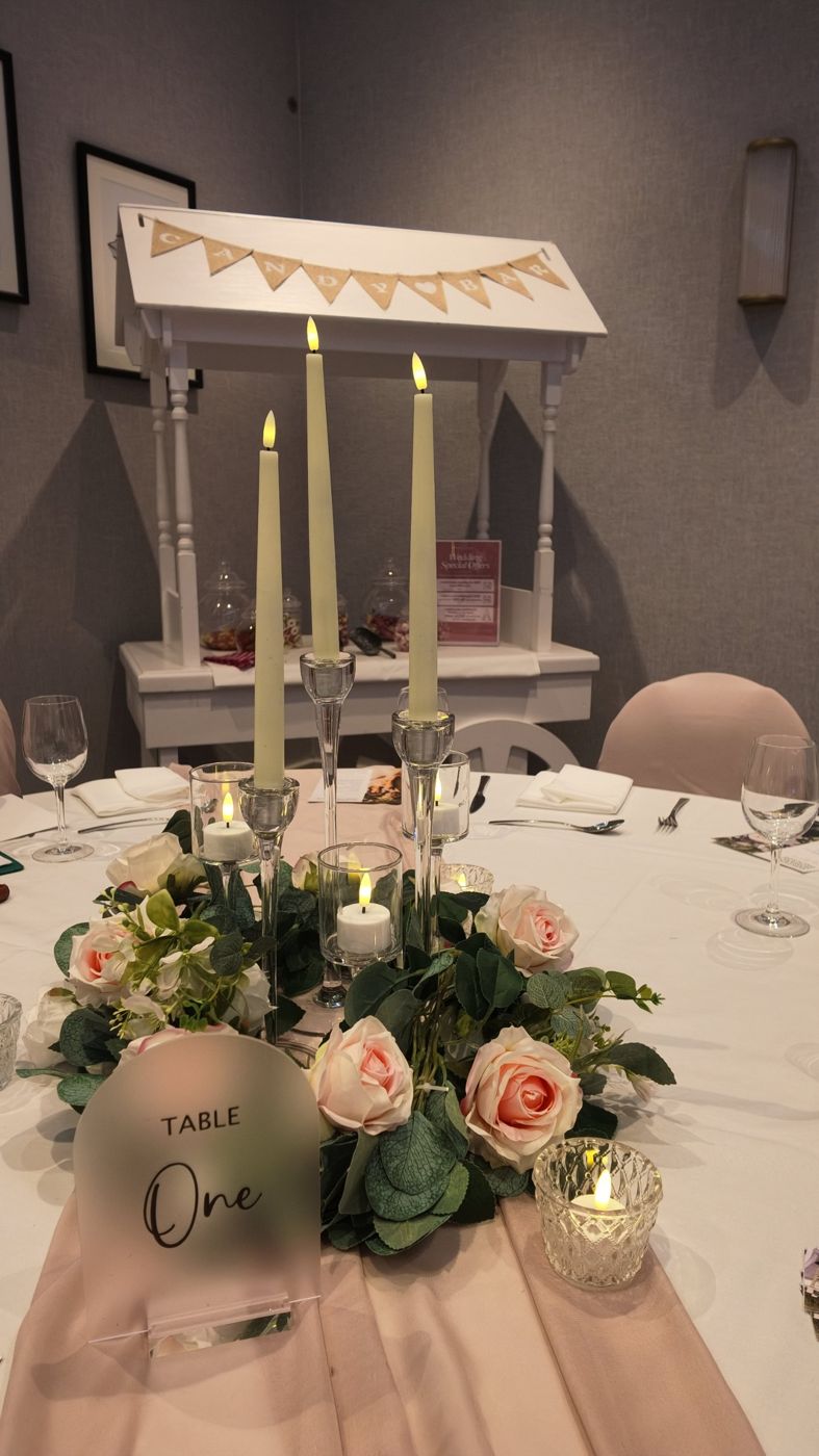 Blush roses and taper candles on a wedding table